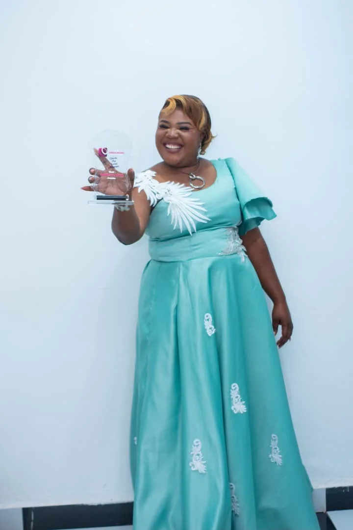 CEO holding an award in a turquoise gown